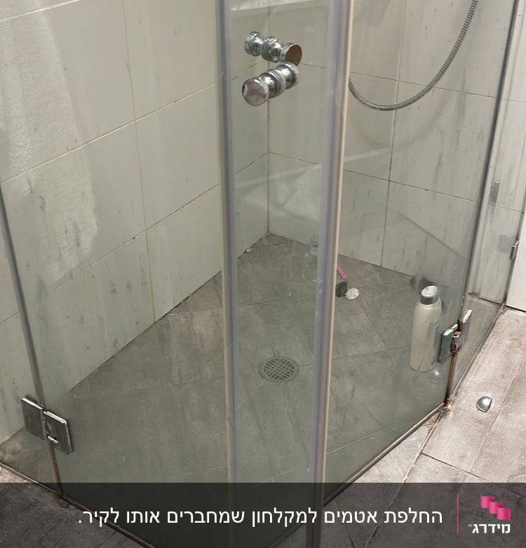 מקלחון זכוכית עם בקבוקי שמפו ומגבת לבנה